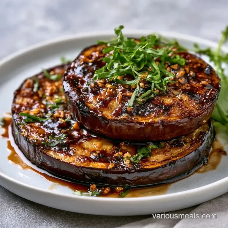 Neatly stacked roasted eggplant rounds topped with crumbled feta, fresh parsley, and a drizzle of dark syrup.