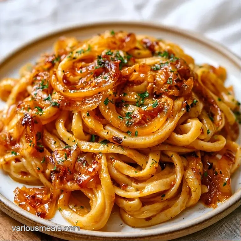 Glossy rigatoni on a shallow plate, draped in melted Gruy&egrave;re and sweet caramel-brown onion strands, dusted with black pepper.