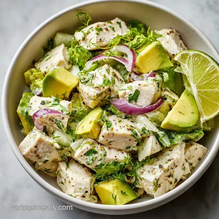 Chicken salad with diced avocado artfully arranged on crisp lettuce, a bright and healthy lunch displayed on a white plate.