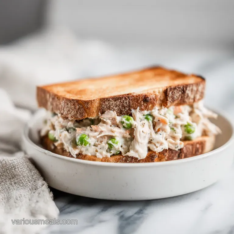 Two tuna melts, browned and bubbly cheese, plated with crisp green lettuce and sliced red tomatoes; toasted bread.