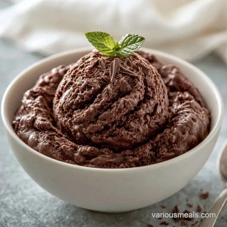Three smooth scoops of cocoa-colored frozen dessert paired with bright red raspberries and a sprig of fresh mint.