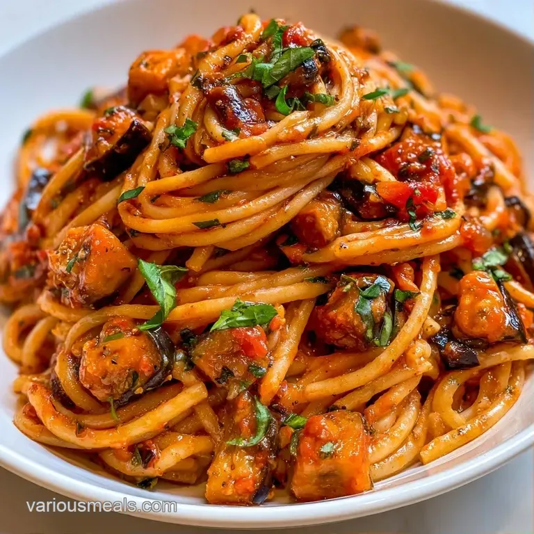Al dente pasta tossed in red sauce, served in a white bowl and garnished with a sprig of fresh, bright green basil.