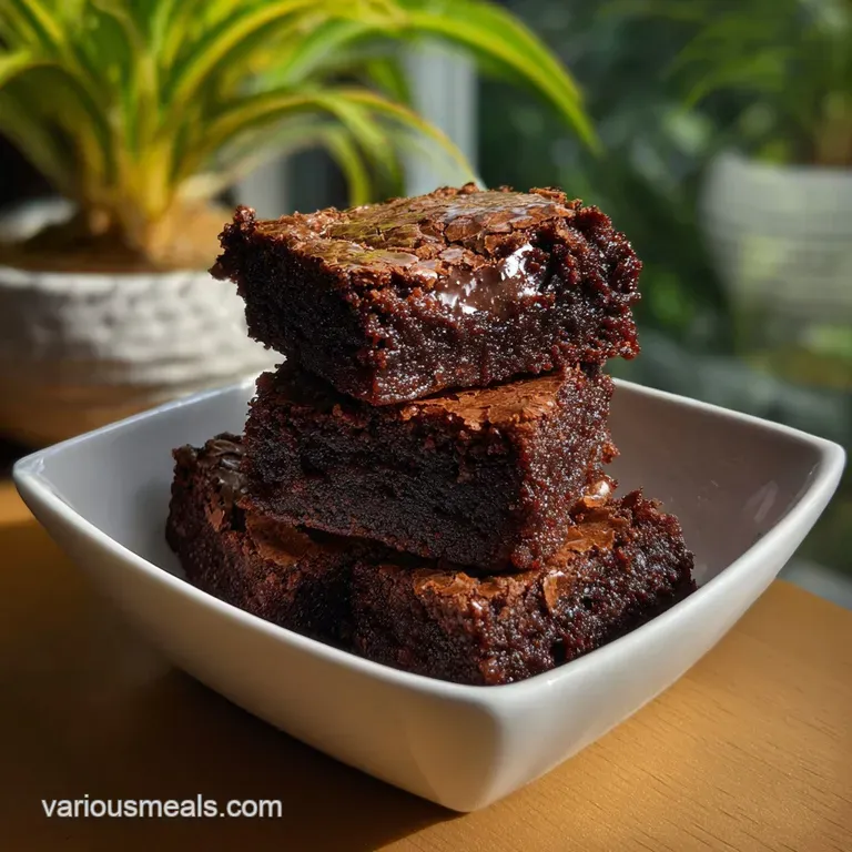 Single, rich brownie on a white plate, dusted with powdered sugar. Shiny, dense crumb with a decadent, satisfying appearance.