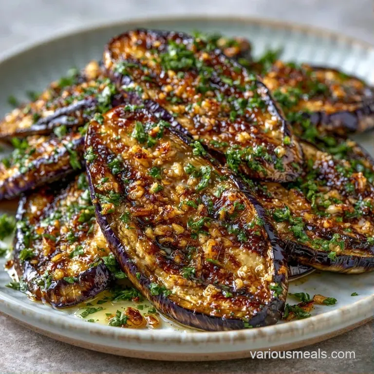 Golden-brown roasted eggplant rounds plated elegantly with a drizzle of oil and a pinch of fresh green parsley.