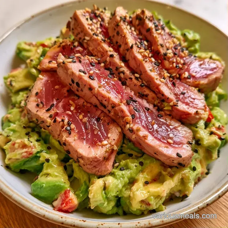 Elegant arrangement of seared tuna and buttery avocado slices garnished with sesame seeds on a white plate.