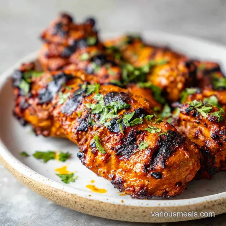 Plated tandoori chicken glistening with spices, nestled on fluffy rice pilaf with a side of cool, creamy raita in a small ...