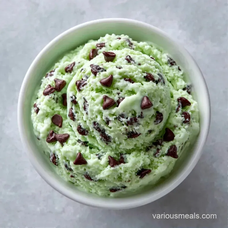 Two smooth scoops of pale cream in a chilled glass bowl, topped with toasted almond slivers and a fresh mint leaf.