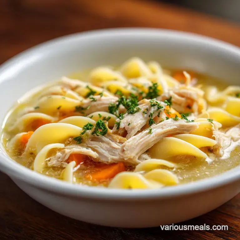 Tender chicken pieces and wide noodles artfully arranged in a rustic bowl, glistening with broth.