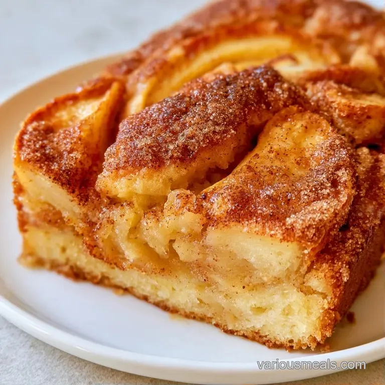 Elegant slice of golden apple cake on a white plate, paired with a dollop of cream and fresh mint leaves.