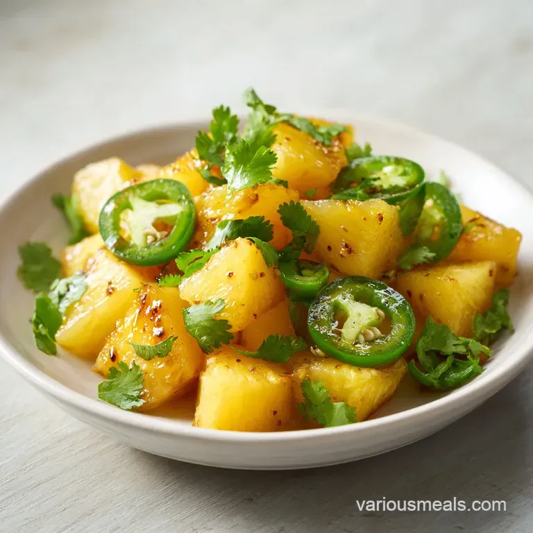 Glossy golden fruit chunks and green chili slices artfully arranged on a minimalist white porcelain platter.