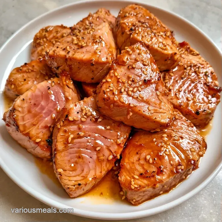 Artistic arrangement of seared tuna slices topped with white sesame seeds and sliced scallions on a slate platter.