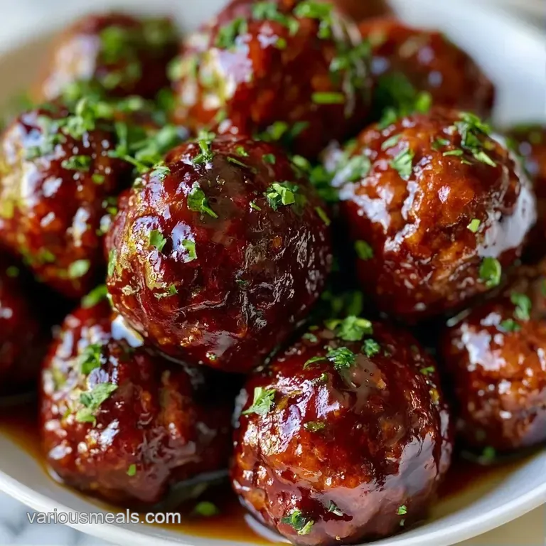 Platter of mahogany-colored glazed meatballs garnished with sesame seeds on a minimalist white ceramic plate.