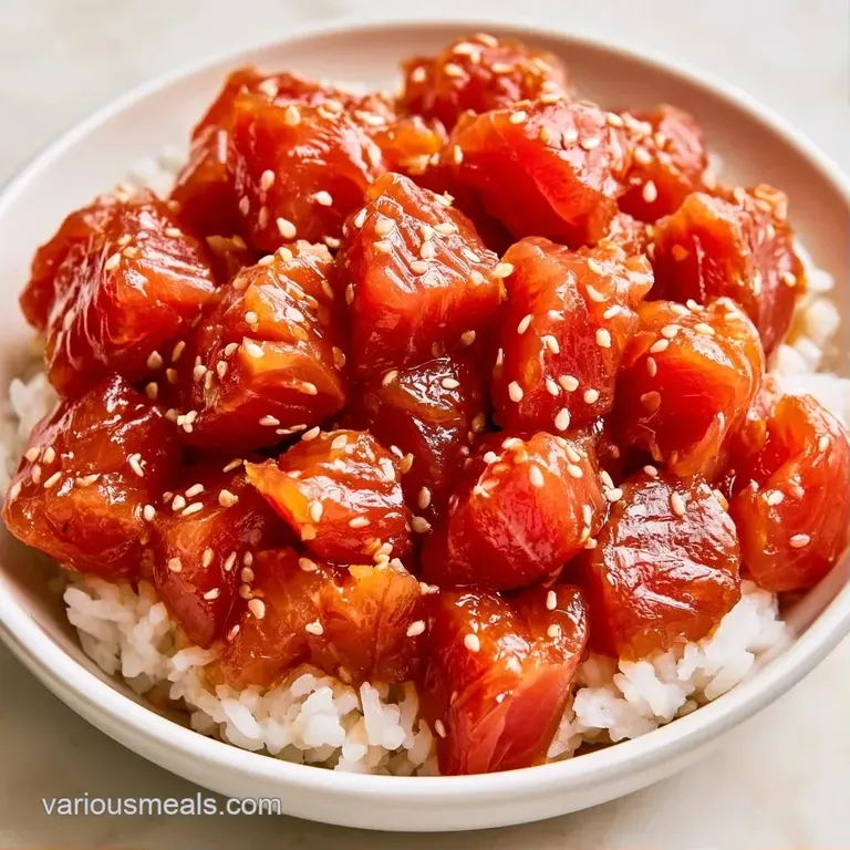 Vibrant sections of red tuna, green edamame, and creamy avocado arranged neatly in a white ceramic bowl on white rice.