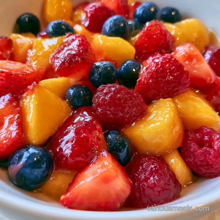 Elegant platter of sliced golden peaches and ruby red berries garnished with sprigs of mint on a marble surface.